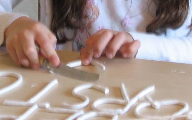 child molding letters with clay